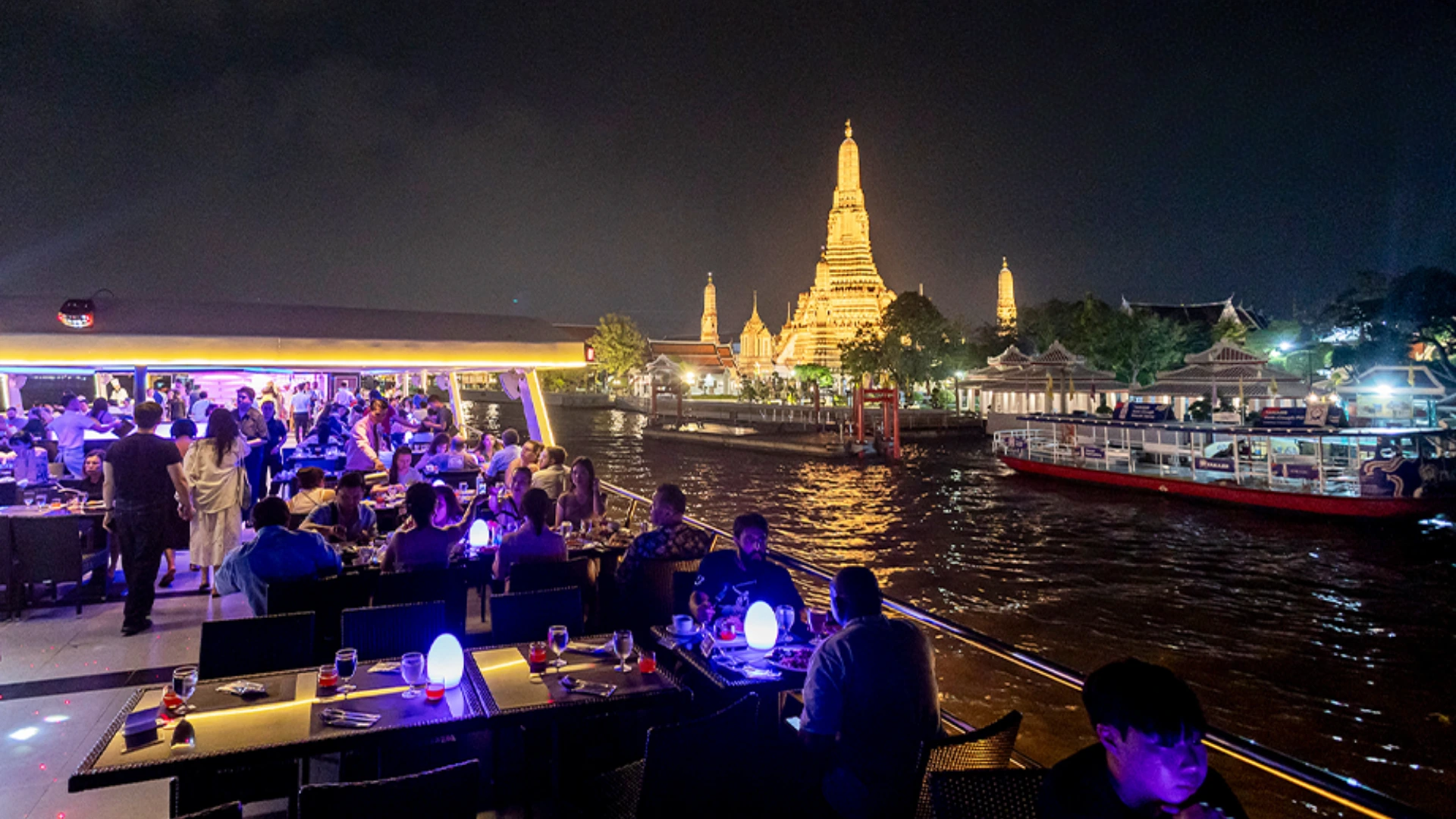 Bangkok riverside landmarks lit up at night from the Chao Phraya cruise