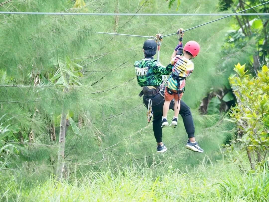 Climber in full safety harness on the canopy obstacle course at Tarzan Adventure Pattaya