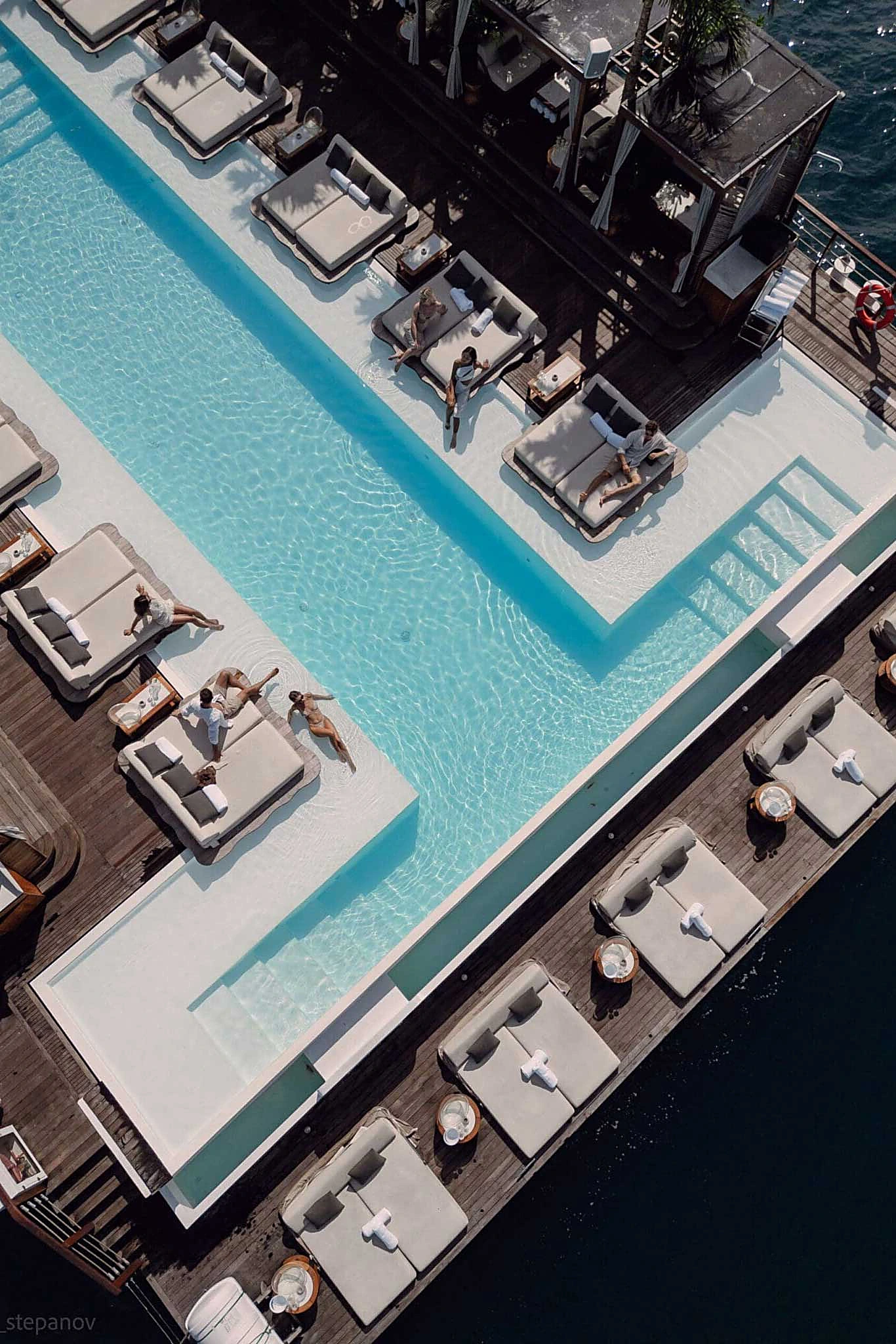 Aerial view of YONA Beach Club&rsquo;s infinity pool and daybeds on the floating deck